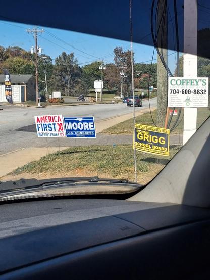 A political sign for Tim Moore for Congress directly next to a Patriot Front sign that says America First.